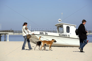 Touristen mit Hunden und Boot am Strand in Ahlbeck an der Ostsee