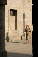 Spanien  El Escorial  aeltere Frau laeuft abends durch die Strassen