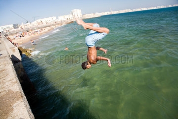 Spanien  Cadiz  ein Junge springt mit einem Salto rueckwaerts ins Wasser