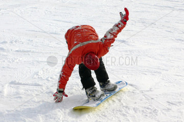 Tirol  ein Junge lernt auf einem Snowboard zu fahren