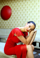 Portrait junge  schoene Frau im roten Kleid in einer Szene-Bar