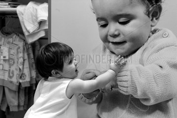 Spanien  kleines Maedchen versucht mit einem Baby auf einem Riesenbild in einer Boutique zu spielen