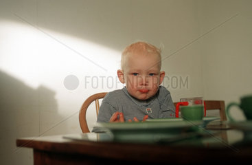 Schmollender kleiner Junge am Fruehstueckstisch