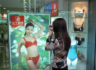 Eine Frau schminkt sich auf der Nanjing Lu in Shanghai