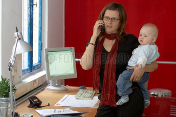 Berufstaetige Mutter mit Baby im Buero