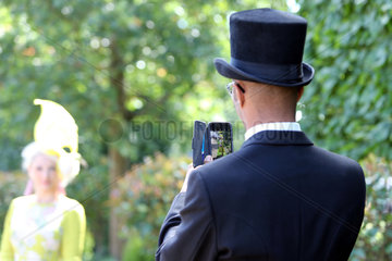 Royal Ascot  Grossbritannien  Mann mit Zylinder macht ein Foto von seiner Frau mit seinem Smartphone