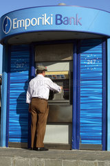 Rhodos  Mann hebt Geld an einem Automaten der Emporiki Bank ab