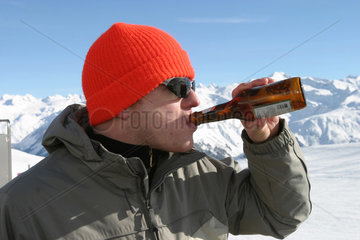 Davos  Junger Mann trinkt Bier auf der Skipiste