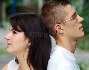 Berlin  ein junges Paar sitzt Ruecken an Ruecken