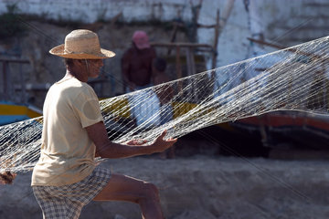 Ein Fischer reinigt sein Netz am Strand  Brasilien