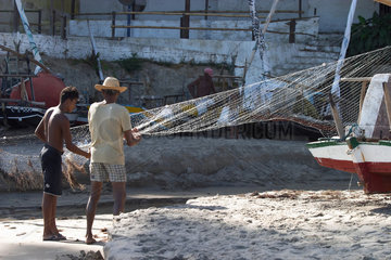 Zwei Fischer reinigen ein Netz in Brasilien
