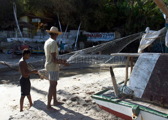 Zwei Fischer reinigen ein Netz in Brasilien