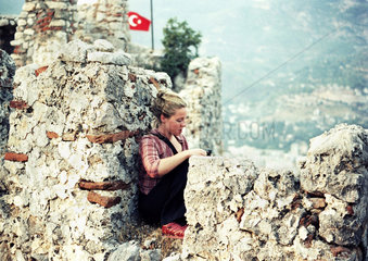 Alanya  eine junge Frau sitzt auf der Festung Alanya Kalesi