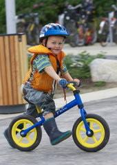 Kleiner Junge mit Schutzhelm auf Laufrad