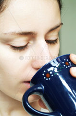 Junge Frau trinkt aus einer Tasse
