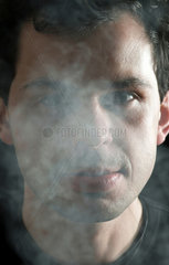 Mann  das Gesicht mit Zigarettenrauch vernebelt
