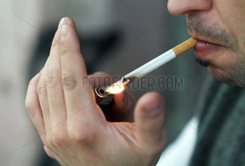 Ein Mann zuendet sich eine Zigarette an