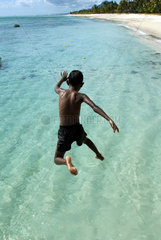 Junge springt am Strand von La Morne Brabant ins Wasser (Mauritius)