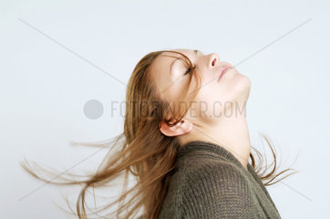 Junge Frau wirft schwungvoll ihr Haar zurueck