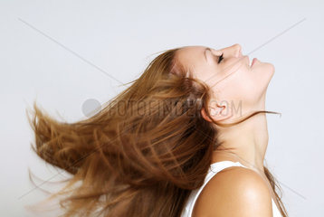 Junge Frau wirft schwungvoll ihr Haar zurueck
