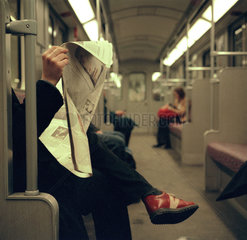 Eine Frau liest in der U-Bahn Zeitung