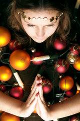 Frau mit Weihnachtsschmuck behangen  die Haende zum Gebet gefaltet