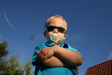 Birkach  Deutschland  Kleinkind posiet mit Schnuller und Sonnenbrille