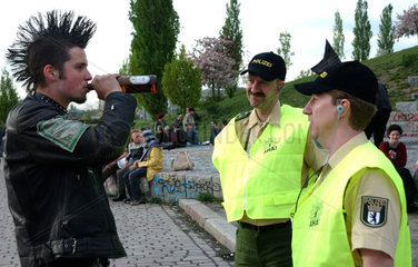 Polizeibeamte im Gespraech mit einem Punk im Berliner Mauerpark