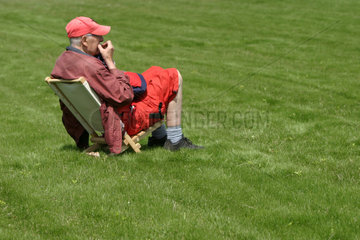 Aelterer Mann sitzt auf einem Klappstuhl