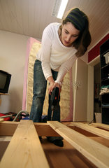 Junge Frau beim Abbauen eines Holzbettes