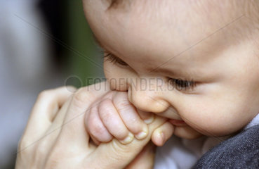 Baby haelt sich an einer Mutterhand fest