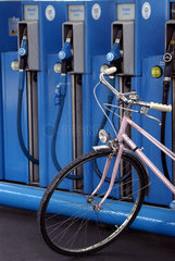Fahrrad vor Zapfsaeulen an einer Tankstelle