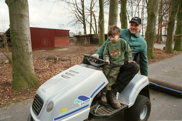 Vater mit Sohn auf einem Rasentraktor  der eine Walze zieht  Deutschland