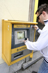 Koeln  Mann kauft Briefmarken am Postautomaten