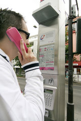 Mann telefoniert am oeffentlichen Muenztelefon der Deutschen Telecom