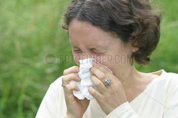 Frau niest in ein Taschentuch