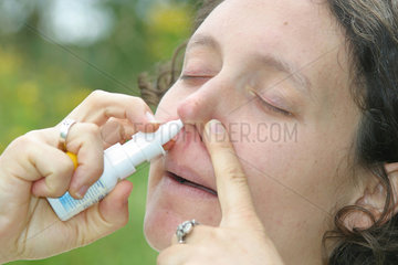 Frau benutzt ein Nasenspray