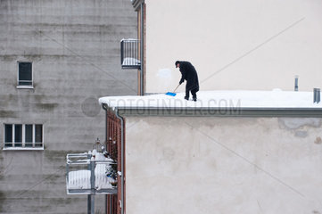 Berlin  Deutschland  ein Mann raeumt Schnee vom Dach