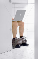 Mann mit Laptop auf dem WC