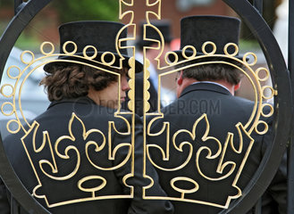 Ascot  Grossbritannien  Maenner mit Zylinder hinter dem Abbild einer Krone in einem Eisenzaun