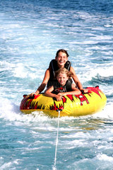 Krk  Mutter mit Kind lassen sich vom Boot auf einem Schwimmreifen ziehen