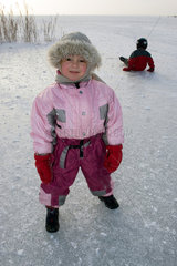 Bad Buchau  ein Kind steht in dicker Winterkleidung auf dem zugefrorenen Federsee