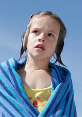 Neuhaus  ein Kind steht in ein Badehandtuch gewickelt am Ostseestrand