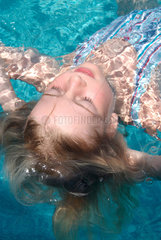 Berlin  Maedchen liegt entspannt auf dem Ruecken im Pool