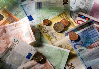Euromuenzen auf durcheinander liegenden Euroscheinen in verschiedenen Nennwerten