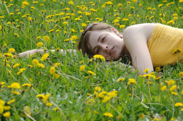 Frau liegt auf einer Blumenwiese