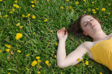 Frau liegt auf einer Blumenwiese