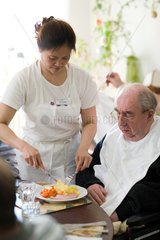 Mainz  eine Pflegerin hilft einem aelteren Mann beim Essen