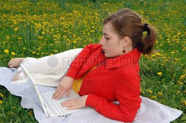 Frau auf einer Blumenwiese mit Laptop