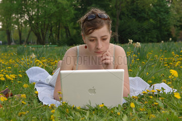 Frau mit ihrem Laptop auf einer Blumenwiese